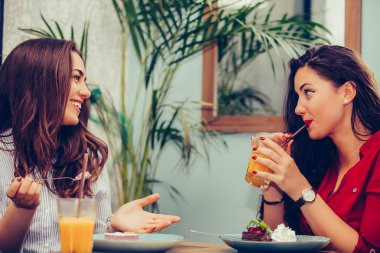 İki güzel genç kadın birlikte meyve suyu ve kek zevk bir 