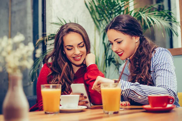 Две молодые женщины, сидящие в кафе, расслабляясь и наблюдая за сометом — стоковое фото