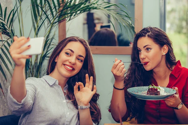 Due ragazza mangiare torte e prendere selfie con smartphone in caffè — Foto Stock