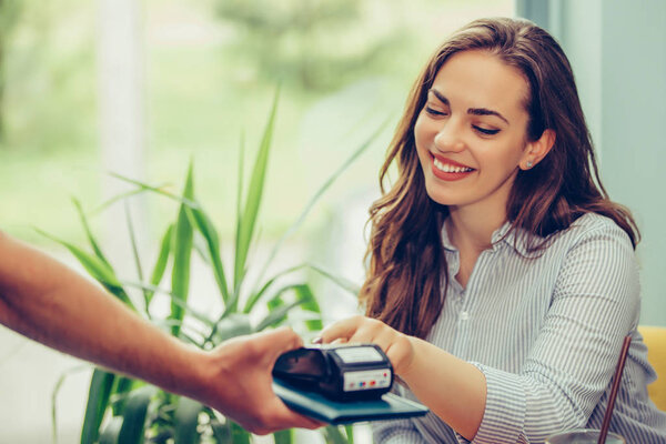Woman entering security pin in credit card reader with waiter st