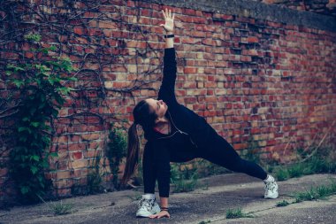 Güzel kız streç egzersizleri yapıyor, BAC tuğla duvar
