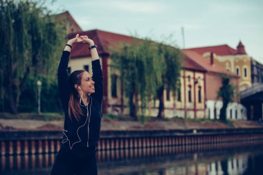 Genç kadın müzik dinlerken kollarını germe yapıyor 