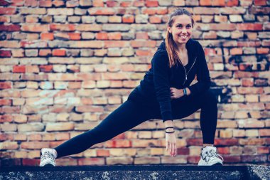 Siyah spor kıyafeti germe egzersizleri yapan genç kadın, b