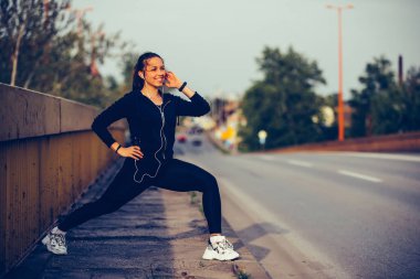 Genç kadın köprüde bacaklarını tretching, iş için hazırlanıyor