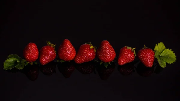 Fresas rojas en línea aisladas sobre fondo negro —  Fotos de Stock