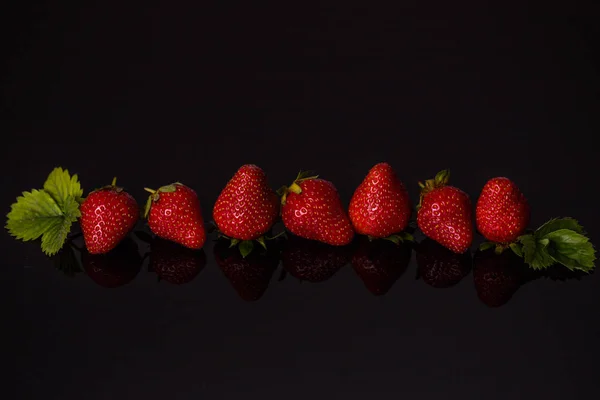 Κόκκινες φράουλες σε γραμμή απομονωμένες σε σκοτεινό φόντο — Φωτογραφία Αρχείου