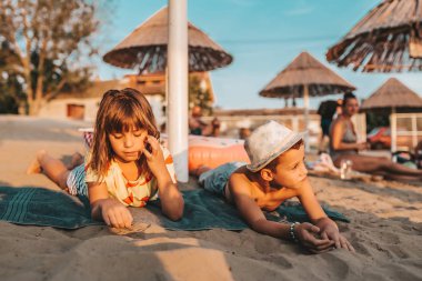 Mutlu çocuklar sahilde bir havlu üzerinde yatan ve bir b zevk