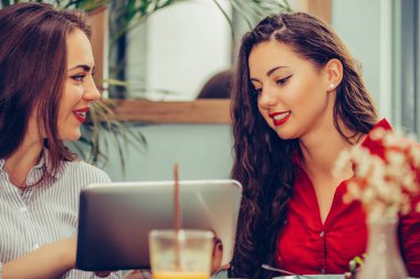 Kafede birlikte tablet kullanan iki kadın arkadaş