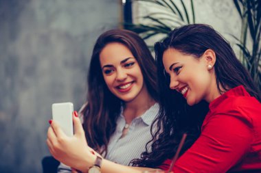 Kafede telefon kullanan iki genç kadın