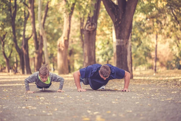 Little boy and his father doing push ups exercises together  in