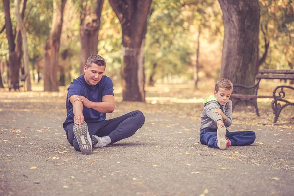 Piccolo ragazzo e suo padre fare stretching esercizio insieme in — Foto Stock