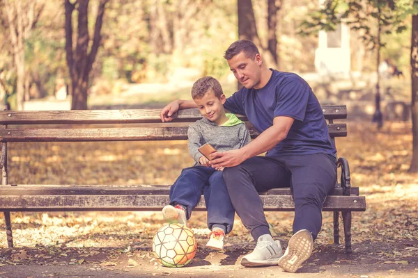 Menino e seu pai fazendo uma pausa após o treino e assistir — Fotografia de Stock