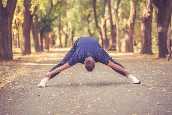 Νεαρός άνδρας κάνει διατάσεις άσκηση στο πάρκο — Φωτογραφία Αρχείου