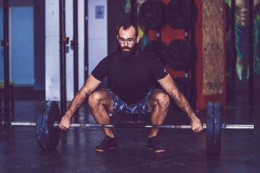 Sakallı adam crossfit spor salonunda ağırlık kaldırma yapıyor