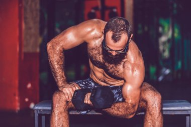 Genç sakallı adam dumbbe ile egzersiz yapıyor spor salonunda çalışıyor