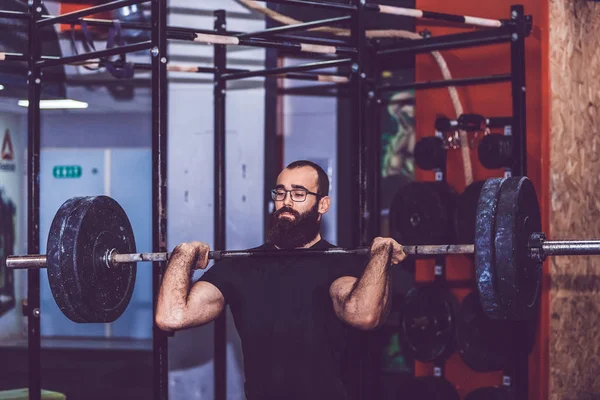 Uomo barbuto sforzo per sollevare pesi pesanti durante un allenamento ses — Foto Stock