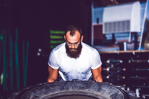 Muscolare barbuto fitness uomo in movimento grande pneumatico nel crossfit g — Foto Stock