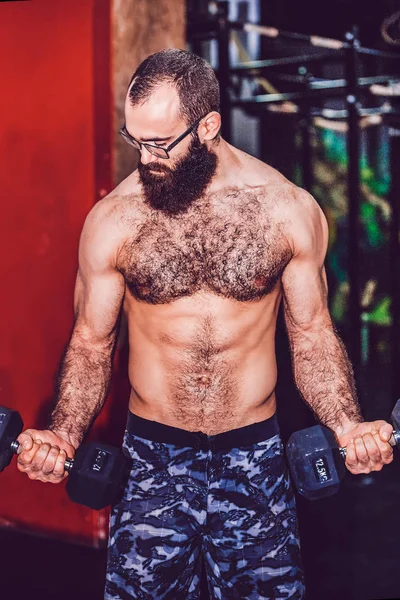 Giovane uomo muscoloso barbuto che lavora in palestra facendo esercizi con — Foto Stock