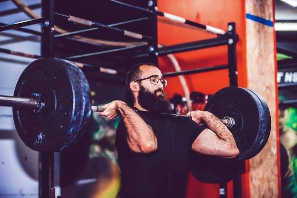 Giovane uomo che si sforza di sollevare pesi pesanti durante un allenamento sessi — Foto Stock