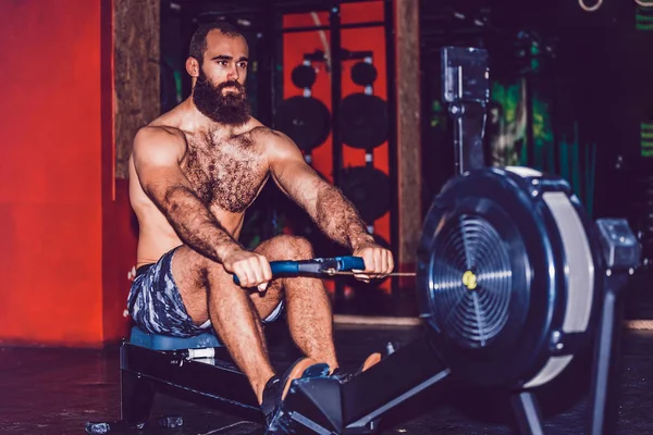 Giovane utilizzando vogatore in palestra — Foto Stock