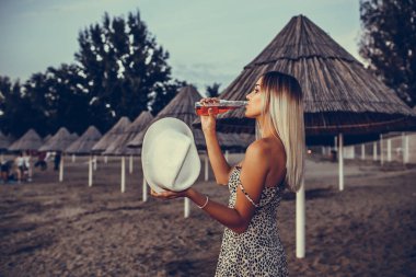 Elinde bir şapka ile genç güzel kadın t yürüme sahiptir
