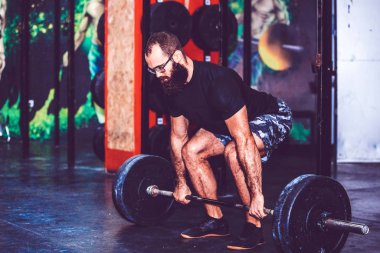 Sakallı genç adam bir spor salonunda egzersiz ağırlık kaldırma