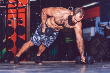 Kas sakallı adam spor salonunda dumbbell ile egzersiz yapıyor