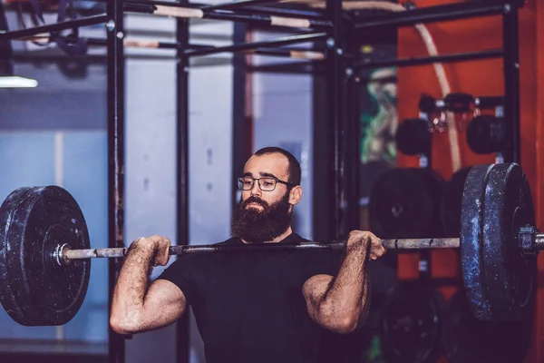 Uomo muscolare che lavora in palestra facendo esercizi con bilanciere — Foto Stock