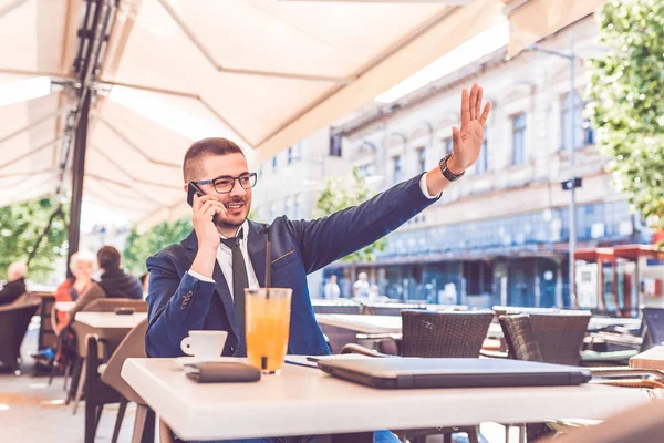 Молодой бизнесмен машет кому-то во время разговора по телефону — стоковое фото