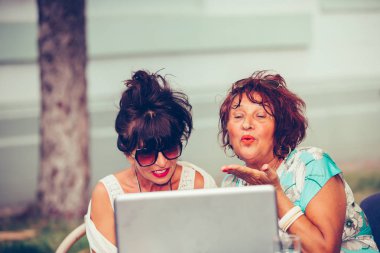 Bir kafede oturan iki mutlu yaşlı kadın bir öpücük online d gönderme