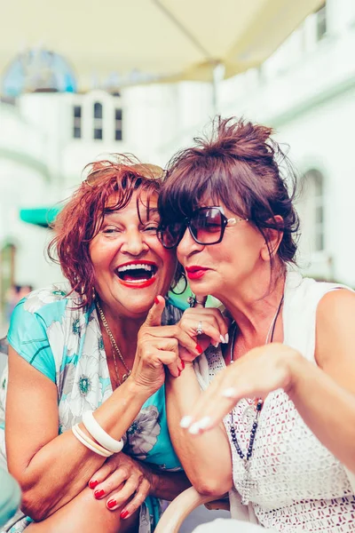 Two happy female senior friends talking, laughing and pointing f — Stock Photo, Image