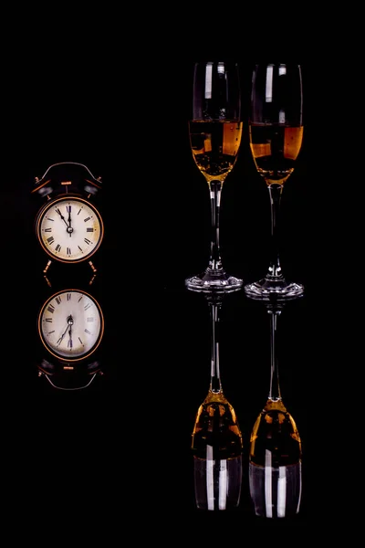 Two wine glasses with champagne and clock  on a black background — Stock Photo, Image