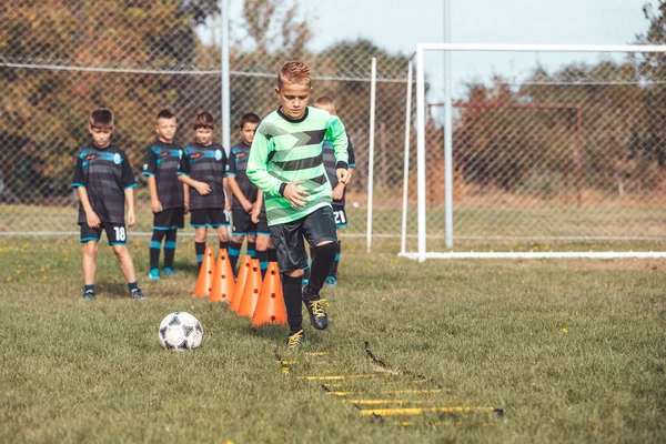 Kid soccer player Jogging and jump between marker for football t