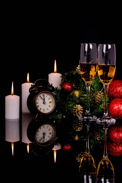 Two wine glasses with champagne, candles clock and Christmas orn