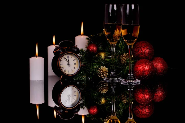 Two wine glasses with champagne, clock, candles and Christmas or