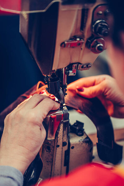 Female hands of an experienced stitching a part of the shoe at a