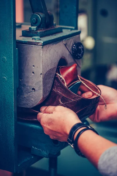 Las manos del trabajador ponen el zapato en una máquina especial de moldeo de zapatos — Foto de Stock