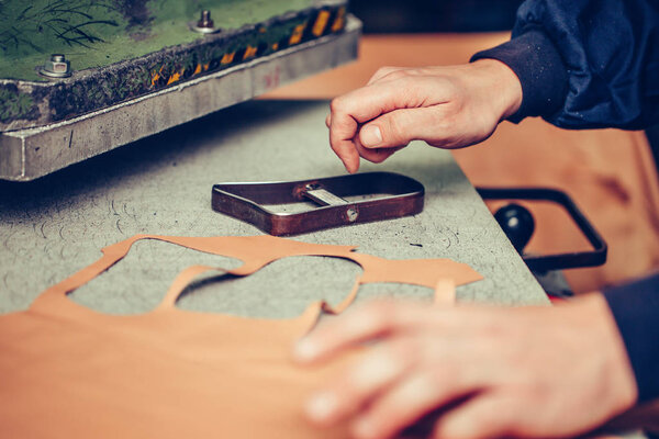 Shoemaker cutting leather in a workshop