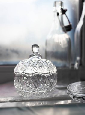 Pencere pervazında yeni yıkanmış cam. Klasik kristal şeker kasesi. Yenilenebilir cam şişeler..
