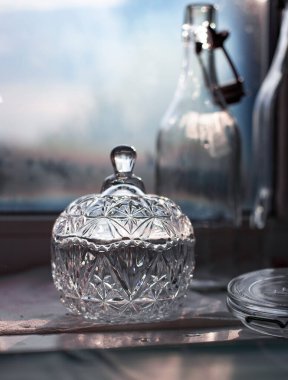 Pencere pervazında yeni yıkanmış cam. Klasik kristal şeker kasesi. Yenilenebilir cam şişeler..
