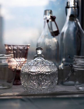 Pencere pervazında yeni yıkanmış cam. Klasik kristal şeker kasesi. Yenilenebilir cam şişeler..