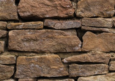 Duvar, dikiş ve çatlaklardan yetişen bitkilerle eski, antik taşlardan yapılmıştır. yakın çekim.