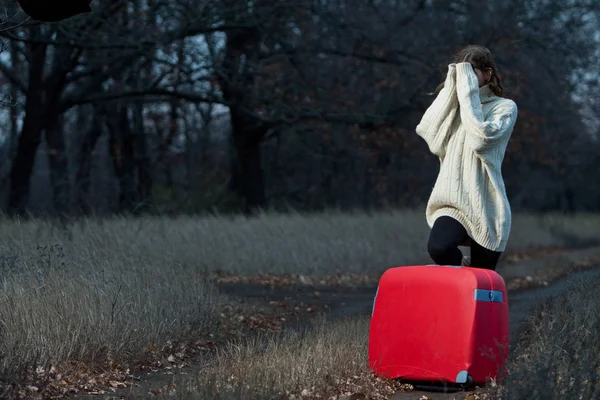 哀伤的妇女与手提箱在孤独的路在晚上 — 图库照片
