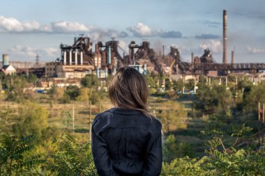 26 Eylül 2018: Endüstriyel tesis duran genç kadın ile duman Mariupol, Ukraine.