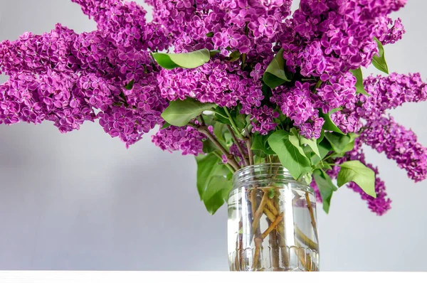 在一个玻璃瓶里的桌子上 花园里的紫丁香一大束 — 图库照片