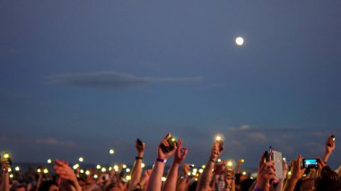 Mariupol, Ukrayna... 7 Temmuz 2017: neşeli kalabalık tezahüratı. Eller yukarı! Siluet, gece, akşam etkinliği