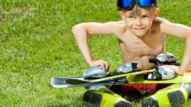 Yeşil çimlerde kayak yapan komik küçük kayakçı. Aktif ve sağlıklı yaşam tarzı kavramı ve kışı beklemek.