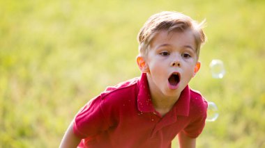Küçük çocuk sabun köpüğü üflüyor.