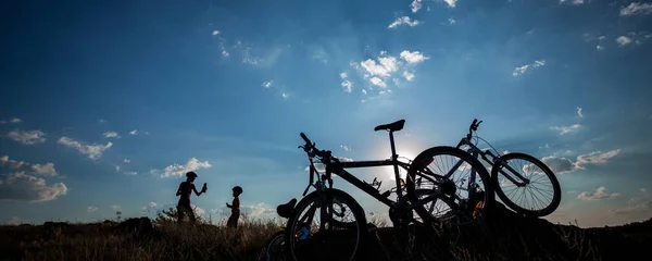 シルエット幸せな母親と息子休憩後長い自転車ドライブオーバー日没空 — ストック写真