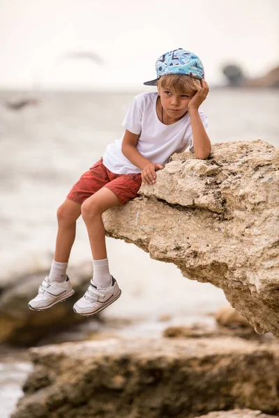 Liebenswerter Kleiner Junge Sitzt Auf Einer Klippe Einem Felsigen Strand — Stockfoto